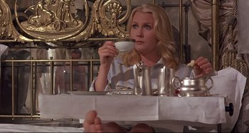 Movie still from “Avanti!” (1972), directed by Billy Wilder – A woman sitting at a table with a cup of coffee; Medium shot, Low angle