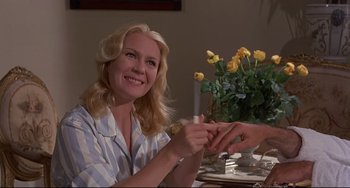 Movie still from “Avanti!” (1972), directed by Billy Wilder – A woman sitting at a dinner table with a flower arrangement; Medium shot, Low angle