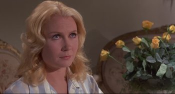 Movie still from “Avanti!” (1972), directed by Billy Wilder – A woman with blonde hair and blue eyes stares at the camera; Close Up shot, Over the shoulder angle