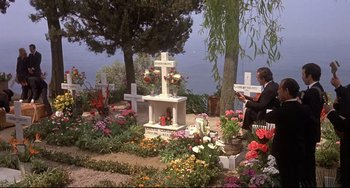 Movie still from “Avanti!” (1972), directed by Billy Wilder – A man sitting in front of a grave in a cemetery; Wide shot, High angle