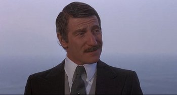 Movie still from “Avanti!” (1972), directed by Billy Wilder – A man in a suit and tie looking at the camera; Close Up shot, Over the shoulder angle