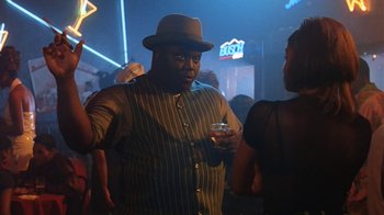 Movie still from “B*A*P*S” (1997), directed by Robert Townsend – A man wearing a hat and holding a glass of wine; Medium shot, Low angle