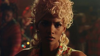 A woman with blonde curly hair wearing gold earrings