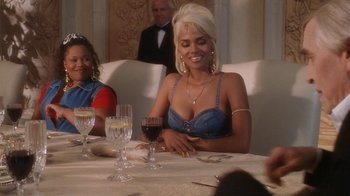 Movie still from “B*A*P*S” (1997), directed by Robert Townsend – A woman sitting at a table with a glass of red wine; Medium shot, Low angle