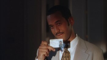 Movie still from “B*A*P*S” (1997), directed by Robert Townsend – A man in a suit holding up his id; Close Up shot, High angle