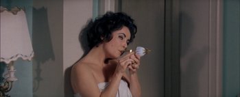 Movie still from “BUtterfield 8” (1960), directed by Daniel Mann – A beautiful woman holding a candle in a bathroom; Close Up shot, High angle