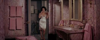 Movie still from “BUtterfield 8” (1960), directed by Daniel Mann – A woman standing in front of a bathroom mirror; Wide shot, High angle