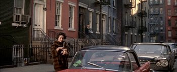Movie still from “BUtterfield 8” (1960), directed by Daniel Mann – A woman standing next to a car on a street; Wide shot, Over the shoulder angle