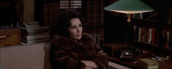 Movie still from “BUtterfield 8” (1960), directed by Daniel Mann – A woman sitting in a chair wearing a fur coat; Close Up shot, High angle