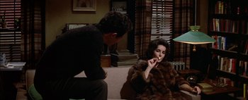 Movie still from “BUtterfield 8” (1960), directed by Daniel Mann – A man and a woman sitting on a couch smoking a cigarette; Medium shot, High angle