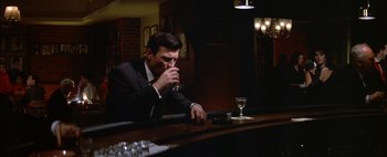 Movie still from “BUtterfield 8” (1960), directed by Daniel Mann – A man sitting at a bar drinking a glass of wine; Medium shot, High angle
