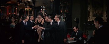 Movie still from “BUtterfield 8” (1960), directed by Daniel Mann – A group of men and women standing around each other; Wide shot, High angle