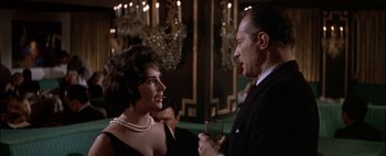 Movie still from “BUtterfield 8” (1960), directed by Daniel Mann – A man and a woman talking in front of chandeliers; Medium shot, Over the shoulder angle