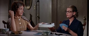 A person sitting at a table holding a box of cake