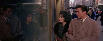Movie still from “BUtterfield 8” (1960), directed by Daniel Mann – A woman wearing a fur coat looking out a window; Medium shot, Over the shoulder angle