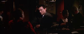 Movie still from “BUtterfield 8” (1960), directed by Daniel Mann – A man sitting at a table in front of a computer; Medium shot, Over the shoulder angle