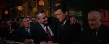 Movie still from “BUtterfield 8” (1960), directed by Daniel Mann – A man in a suit and tie hugging another man in a suit and tie; Medium shot, Over the shoulder angle