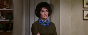 Movie still from “BUtterfield 8” (1960), directed by Daniel Mann – A woman wearing a green sweater and blue necklace; Close Up shot, Over the shoulder angle