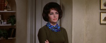 Movie still from “BUtterfield 8” (1960), directed by Daniel Mann – A woman wearing a green sweater and a blue necklace; Close Up shot, Over the shoulder angle