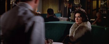 Movie still from “BUtterfield 8” (1960), directed by Daniel Mann – A woman sitting at a table in front of two men; Medium shot, Over the shoulder angle