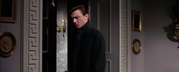 Movie still from “BUtterfield 8” (1960), directed by Daniel Mann – A man standing in front of a door wearing a black coat; Medium shot, Low angle