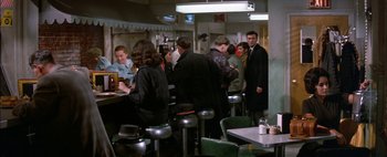 Movie still from “BUtterfield 8” (1960), directed by Daniel Mann – A group of people standing around a restaurant; Wide shot, Over the shoulder angle