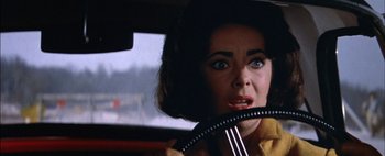 Movie still from “BUtterfield 8” (1960), directed by Daniel Mann – A woman in a yellow shirt is driving a car; Close Up shot, Over the shoulder angle
