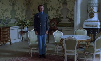 Movie still from “Babette's Feast” (1987), directed by Gabriel Axel – A man dressed in a uniform standing in a room; Wide shot, Low angle