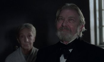 An older man and a younger woman in a dark room