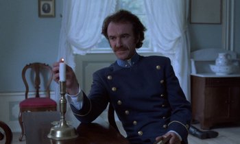 Movie still from “Babette's Feast” (1987), directed by Gabriel Axel – A man sitting at a table with a candle in front of him; Medium shot, Low angle