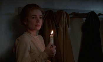 Movie still from “Babette's Feast” (1987), directed by Gabriel Axel – A woman holding a lit candle in a dimly - lit room; Close Up shot, Over the shoulder angle