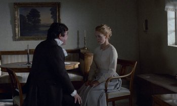 Movie still from “Babette's Feast” (1987), directed by Gabriel Axel – A man and a woman sitting on a chair in front of a painting; Medium shot, Over the shoulder angle