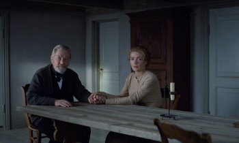 Movie still from “Babette's Feast” (1987), directed by Gabriel Axel – A man and a woman sitting at a wooden table; Medium shot, Over the shoulder angle
