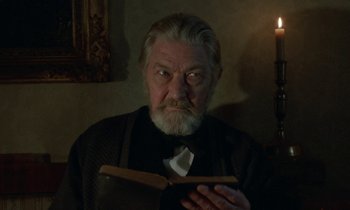 Movie still from “Babette's Feast” (1987), directed by Gabriel Axel – An old man with a beard and a bow tie is holding a book; Close Up shot, Low angle