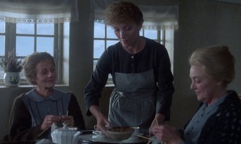 Movie still from “Babette's Feast” (1987), directed by Gabriel Axel – A woman standing at a table with a bowl of food; Medium shot, High angle