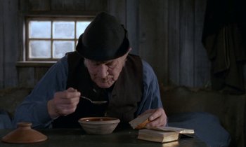 Movie still from “Babette's Feast” (1987), directed by Gabriel Axel – An old man sitting at a table eating a bowl of soup; Medium shot, High angle