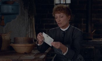 Movie still from “Babette's Feast” (1987), directed by Gabriel Axel – A woman in a priest's outfit is holding a piece of paper in her hands; Medium shot, High angle