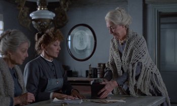 Movie still from “Babette's Feast” (1987), directed by Gabriel Axel – Two older women sitting at a table looking at papers; Medium shot, Over the shoulder angle