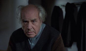 Movie still from “Babette's Feast” (1987), directed by Gabriel Axel – An old man with a gray beard is looking at the camera; Close Up shot, Low angle