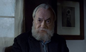 Movie still from “Babette's Feast” (1987), directed by Gabriel Axel – An old man with a beard and a gray jacket; Close Up shot, Low angle
