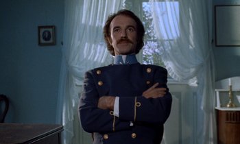 Movie still from “Babette's Feast” (1987), directed by Gabriel Axel – A man in a uniform standing with his arms crossed; Medium shot, Low angle