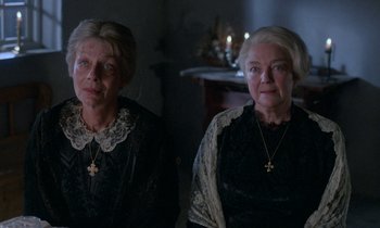 Movie still from “Babette's Feast” (1987), directed by Gabriel Axel – Two older women in black dresses with crosses on them; Medium shot, High angle