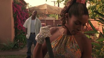Movie still from “Baby Boy” (2001), directed by John Singleton – A man and a woman in a yard with an umbrella; Medium shot, Over the shoulder angle
