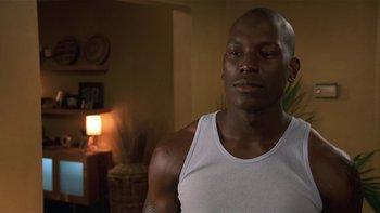 Movie still from “Baby Boy” (2001), directed by John Singleton – A person wearing a tank top in a room; Close Up shot, Over the shoulder angle