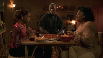 Movie still from “Baby Boy” (2001), directed by John Singleton – A group of people sitting at a wooden table; Medium shot, Over the shoulder angle