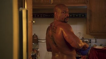Movie still from “Baby Boy” (2001), directed by John Singleton – A man with a tattoo on his back standing in a kitchen; Medium shot, Low angle