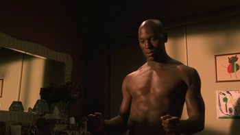 Movie still from “Baby Boy” (2001), directed by John Singleton – A man standing in front of a mirror in a room; Medium shot, Low angle