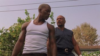 Movie still from “Baby Boy” (2001), directed by John Singleton – Two men standing next to each other in front of a building; Medium shot, Low angle