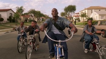 Movie still from “Baby Boy” (2001), directed by John Singleton – A group of people riding bikes down a street; Wide shot, Low angle