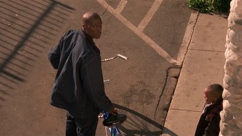 Movie still from “Baby Boy” (2001), directed by John Singleton – A man riding a bike down a street; Medium shot, High angle